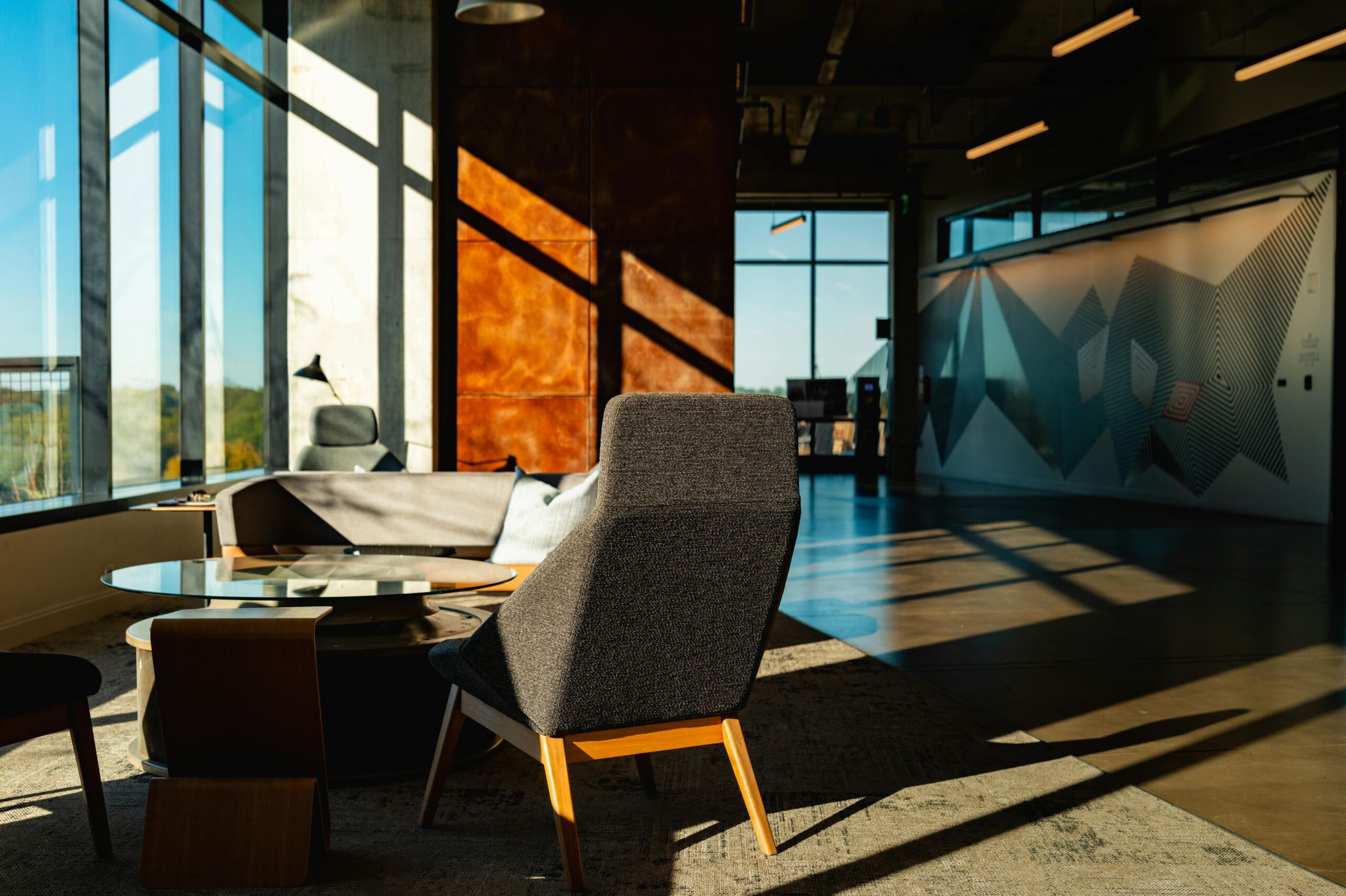 A cozy office lit with the afternoon sunilight, with the table and chairs set up by the floor-to-ceiling windows.